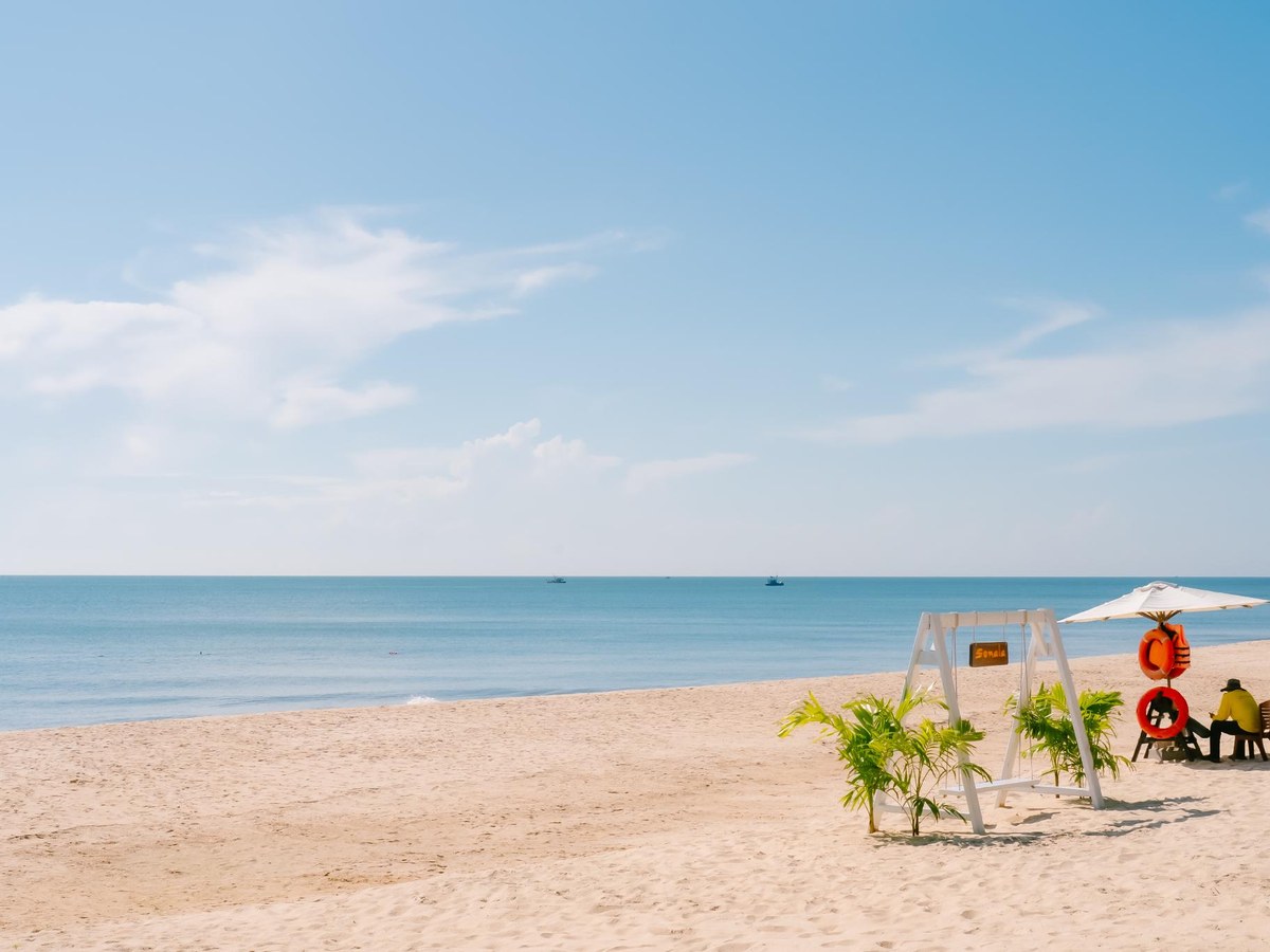Sandy beach with a white lifeguard chair, a beach umbrella and a calm turquoise sea