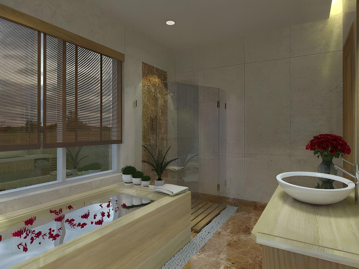 Spa bathtub strewn with red petals in a pale stone room with wooden blinds