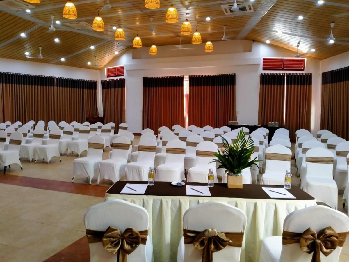 Large function room set with rows of white chairs tied with brown sashes facing a stage
