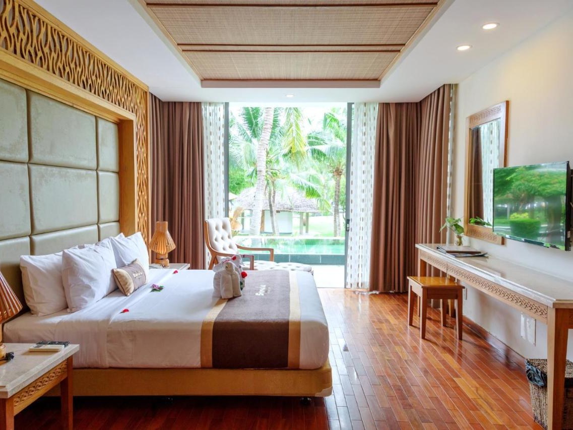 Villa bedroom with a wooden floor, a large bed and glass doors opening onto a terrace