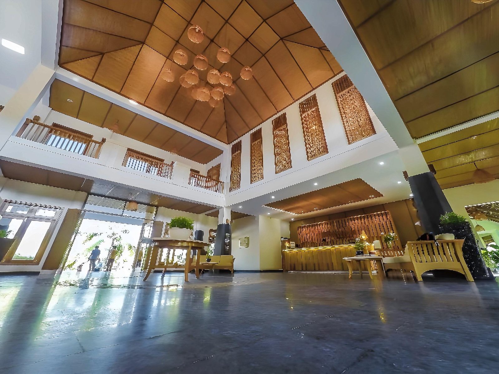 Open lobby under a high pitched timber roof, with a grey stone floor, carved wooden screens and seating