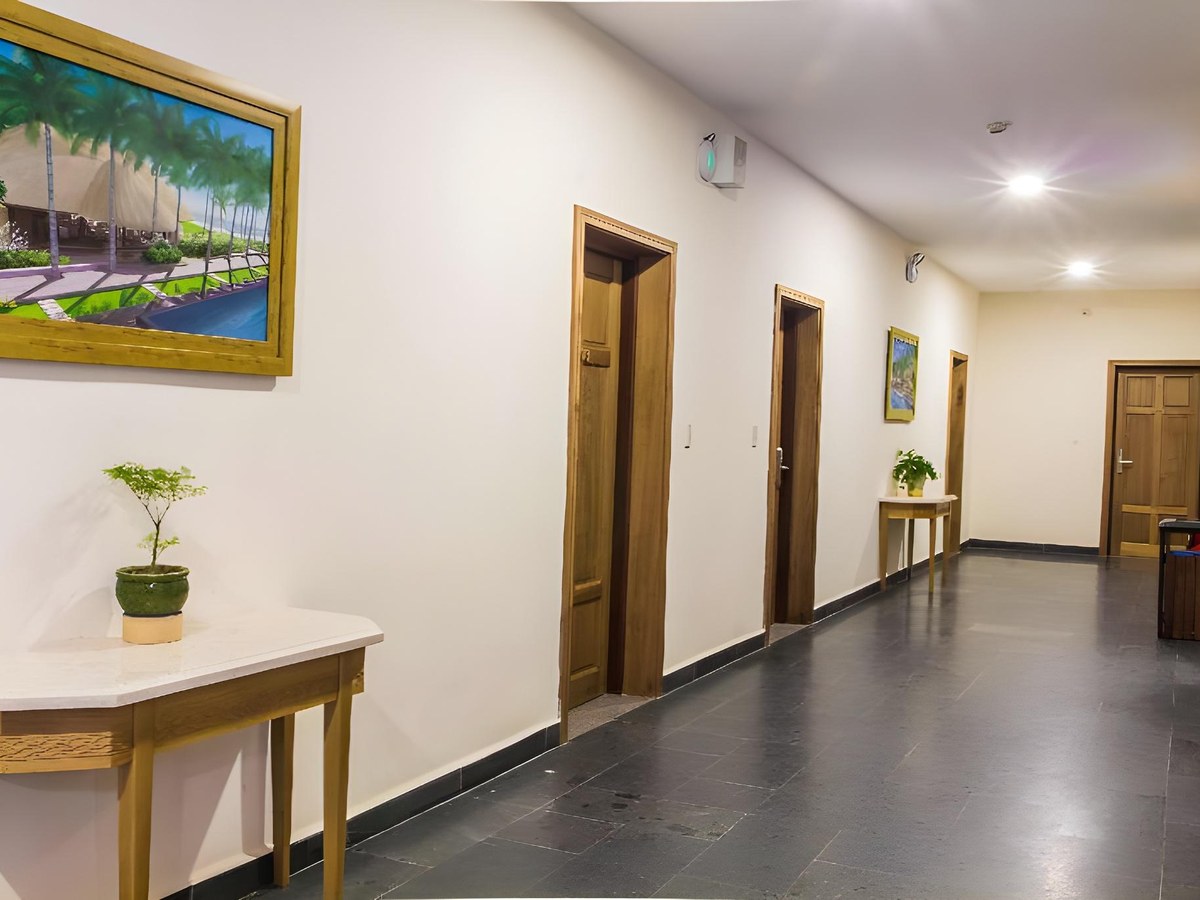Plain tiled hotel corridor with wooden doors and a small table with a plant